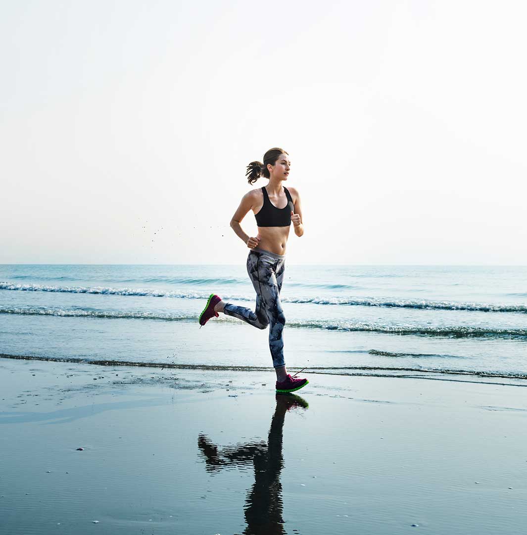 Woman running on a beach with ocean waves in the background